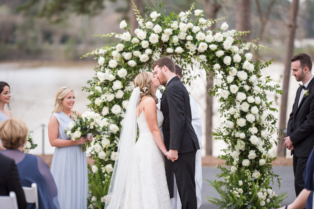 big eddy club wedding, bride and groom in front of floral arch first kiss