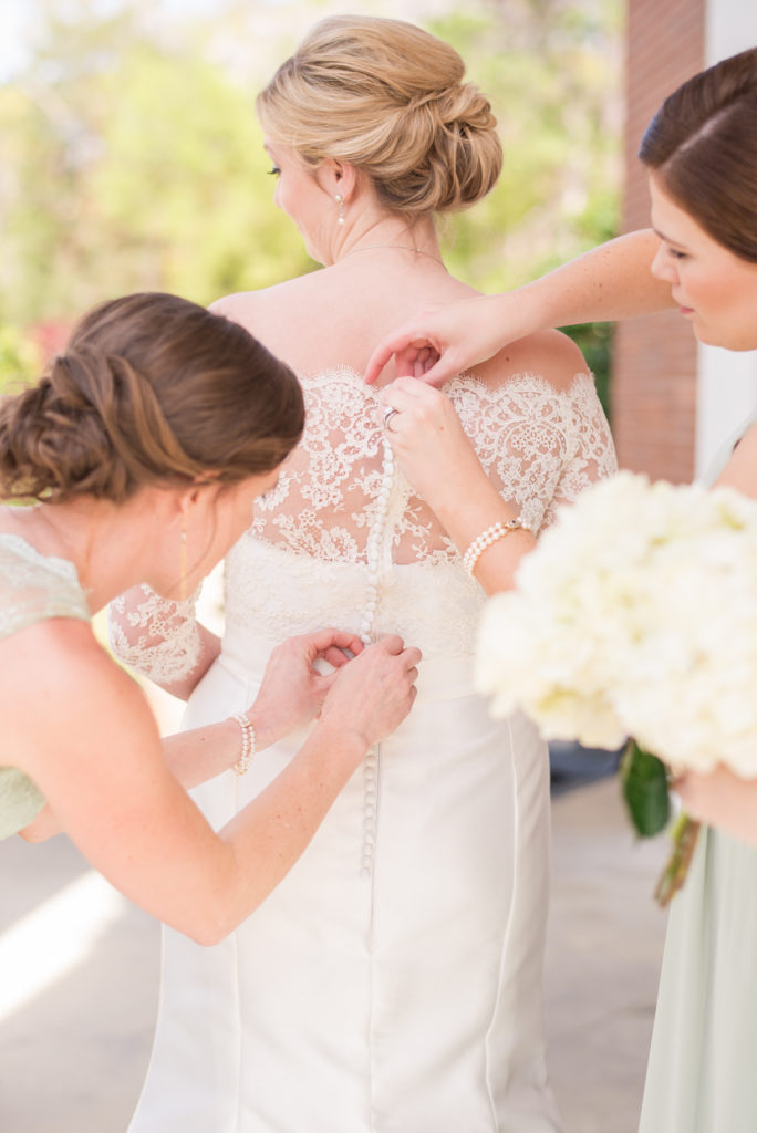columbus georgia wedding photographer bridesmaids helping bride into lace dress outside