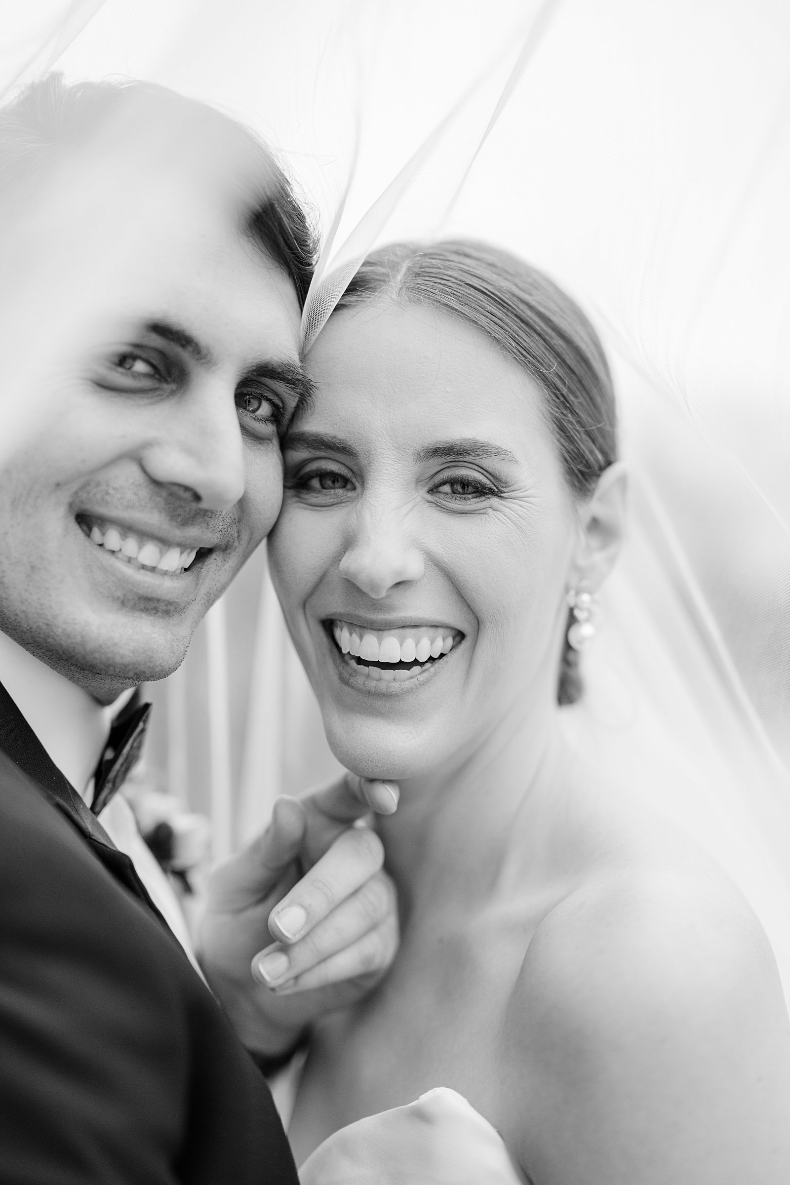colorful winter wedding in columbus, ga - bride and groom laughing under the veil in black and white 