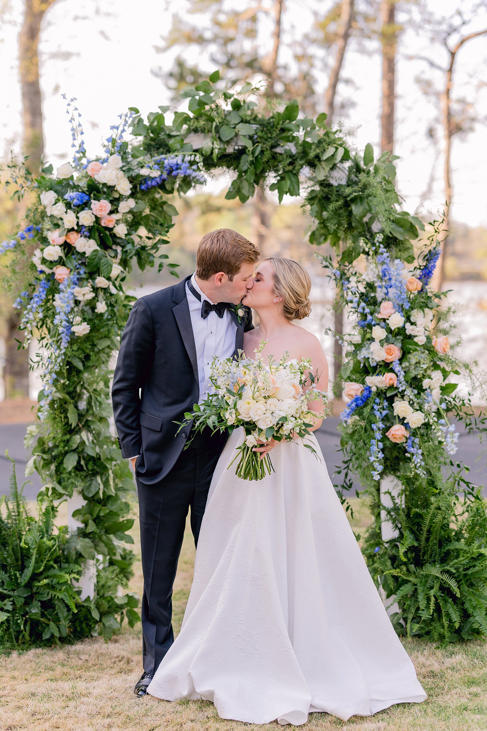 Outdoor Spring Wedding at the Big Eddy Club in Columbus, Ga kissing under a floral arch 